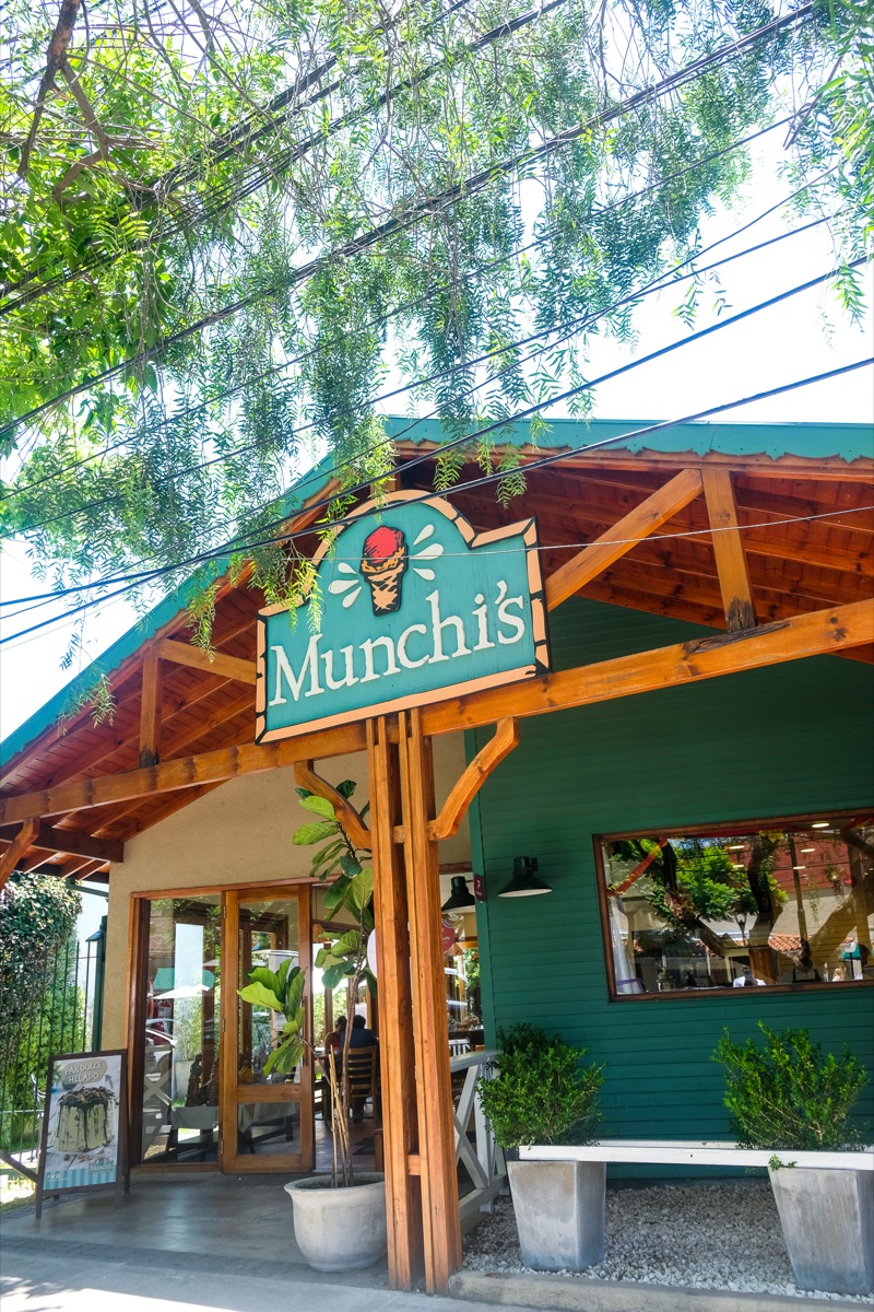 Un local de Munchi’s con su cartel verde bajo los árboles